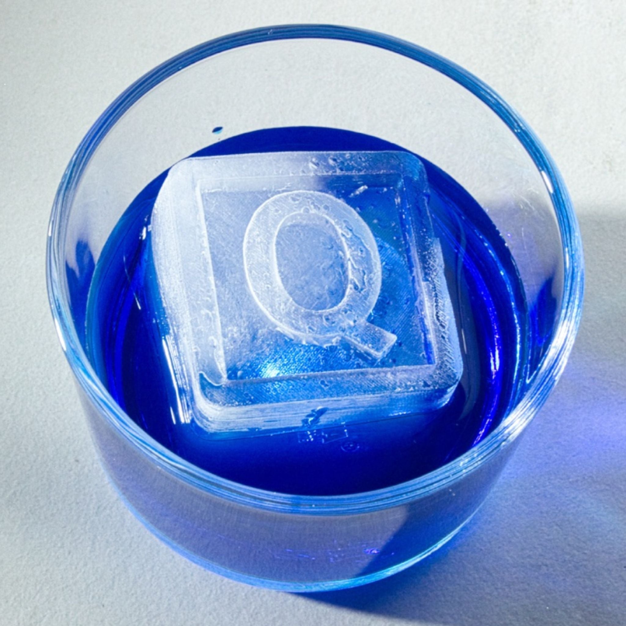 Personalised ‘R’ ice cube in blue cocktail glass – a fun and thoughtful present for whiskey or bourbon enthusiasts.