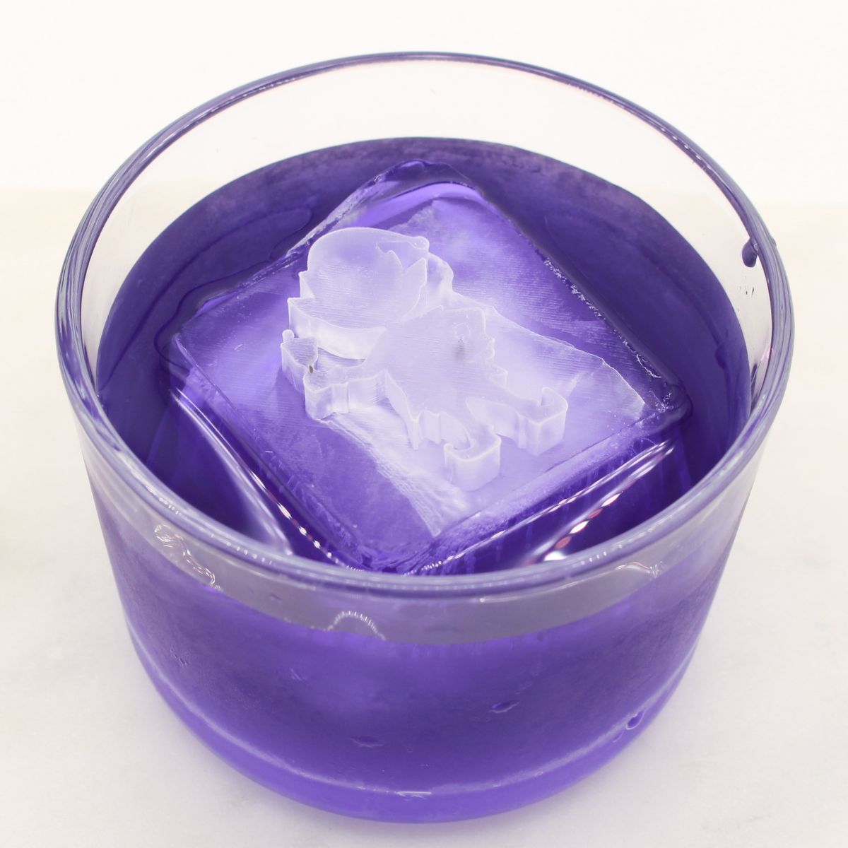 Purple cocktail with a detailed elf-shaped ice cube, perfect for holiday entertaining and festive drinks.