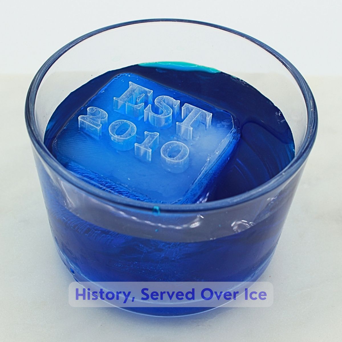Blue cocktail with custom EST 2020 ice cube celebrating company launch year - corporate anniversary ice cubes