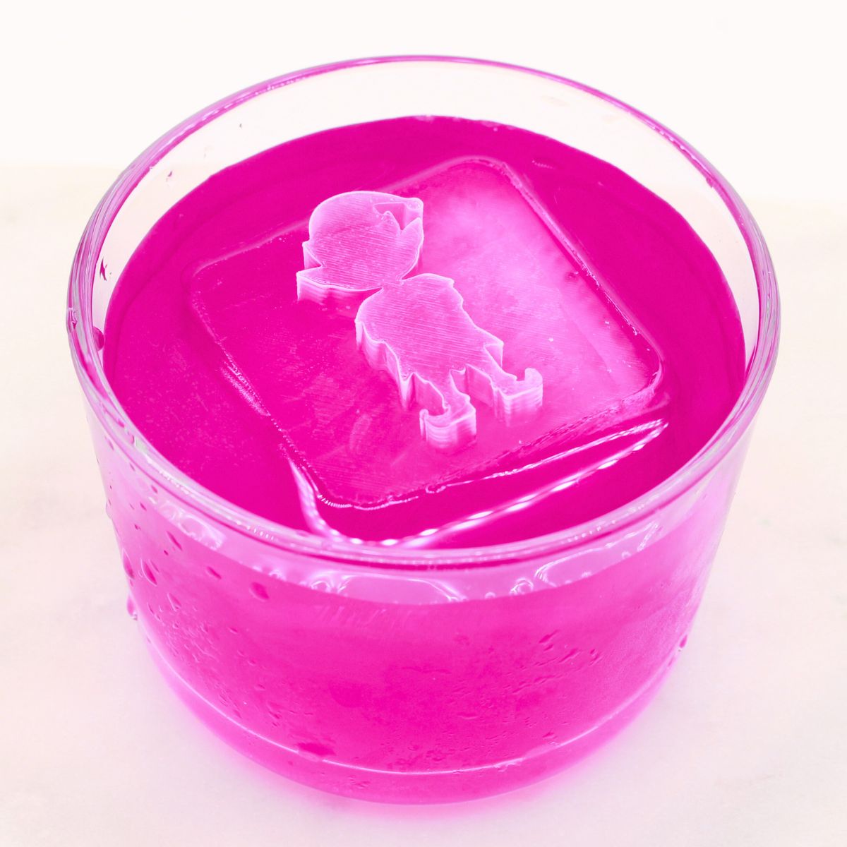 Elf-shaped ice cube resting in a bright pink drink, creating a fun and cheerful festive cocktail presentation.