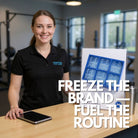 Smiling gym receptionist behind a front desk beside a tabletop sign showing a royal-blue 6-cube silicone ice tray with “IRON FUEL” dumbbell logo cubes; promotional gym merchandise scene.