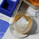 Custom ice cube with the name "LEVI" in a whiskey glass, next to a blue silicone tray and liquor bottle – ideal personalised gift for men