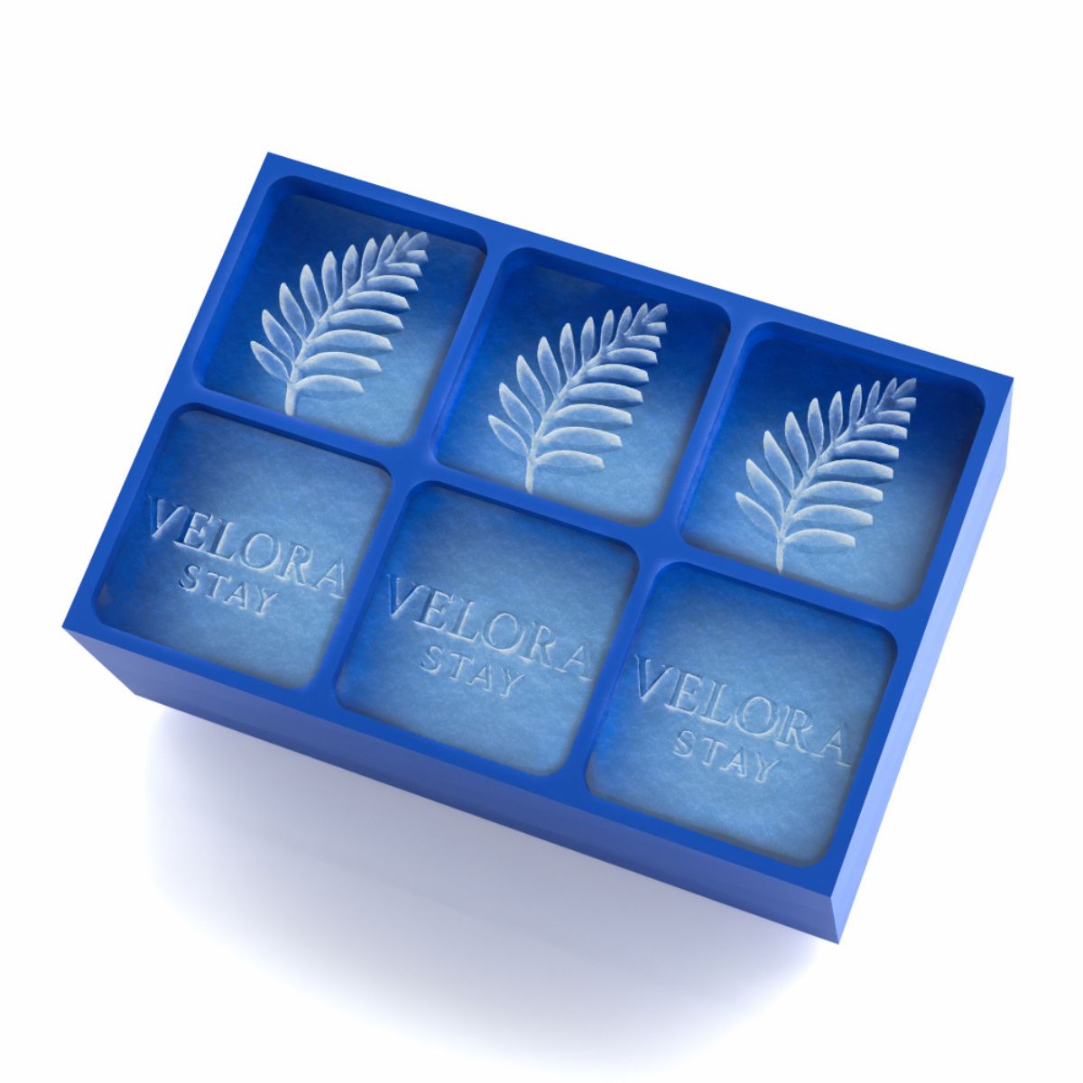 Close view of 45 mm logo ice cubes showing the Velora Stay leaf and wordmark inside a royal-blue 6-cube trayβperfect for hotel welcome drinks and minibar service.