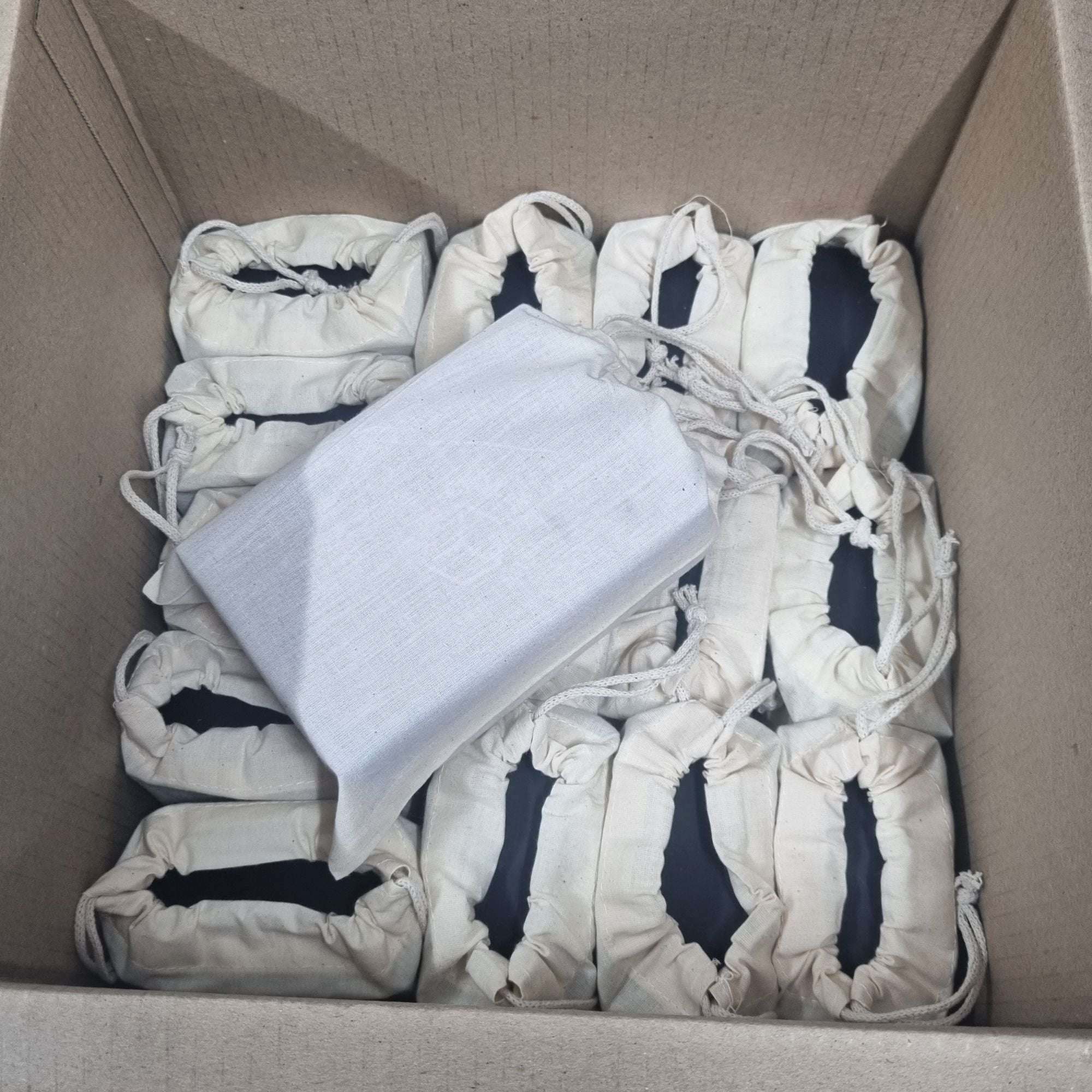 A box of custom ice trays individually packed in cloth drawstring bags, ready for small-batch or bulk orders from Chilled Out Creations.