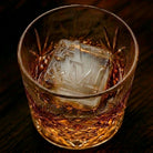 Close-up of a large custom A&M monogram ice cube in a rocks glass of whiskey