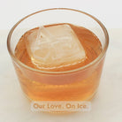 Glass of amber whisky with a personalised ice cube engraved with two initials and a heart, ideal for anniversaries or date nights.