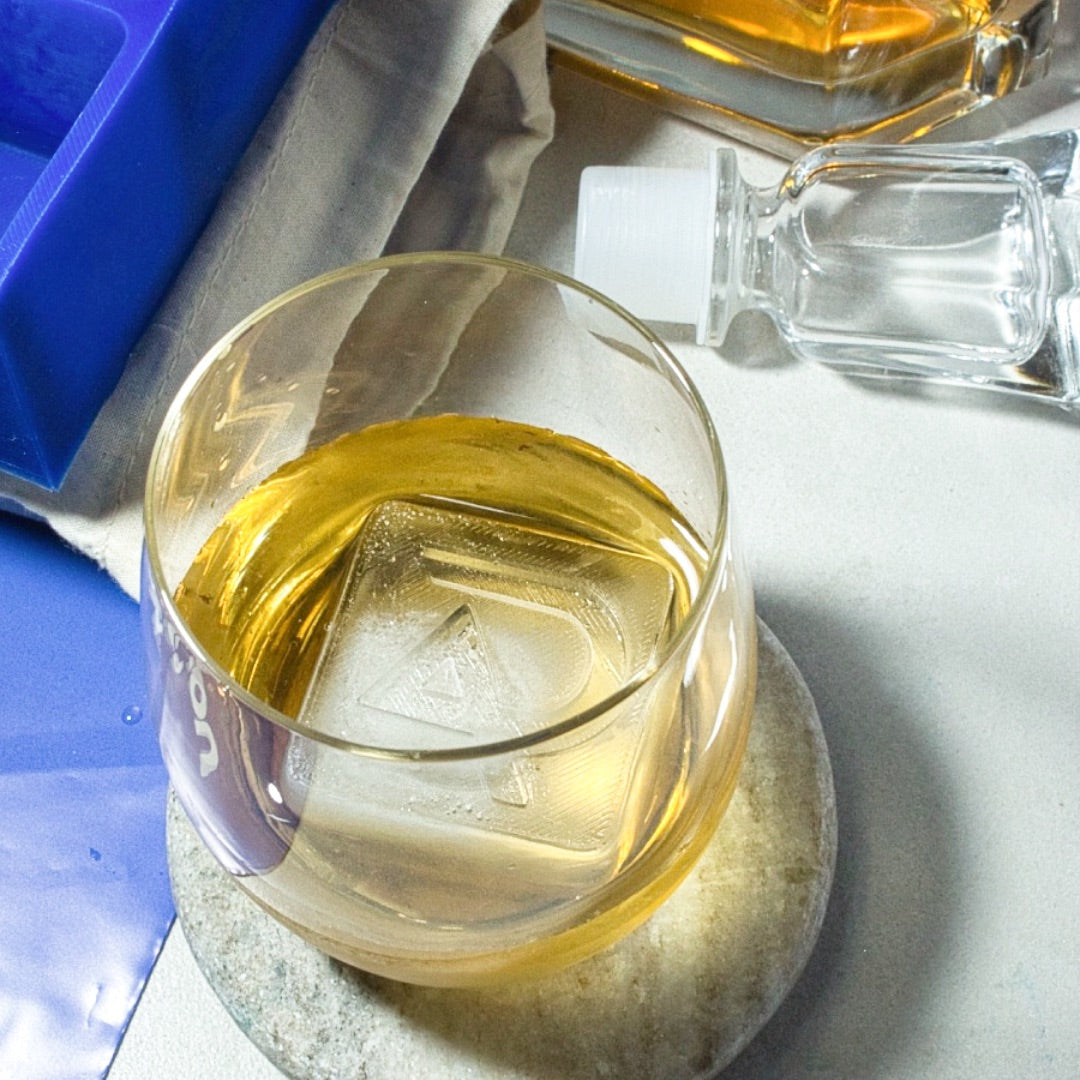 Custom AP logo ice cube served in a whiskey glass beside a silicone tray – ideal for branded drink presentations or executive gifting.