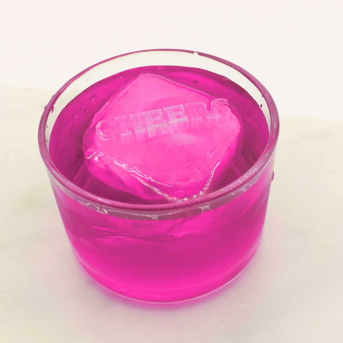 A bright pink drink featuring a raised “CHEERS” ice cube, ideal for party toasts, events, and colourful cocktail moments.