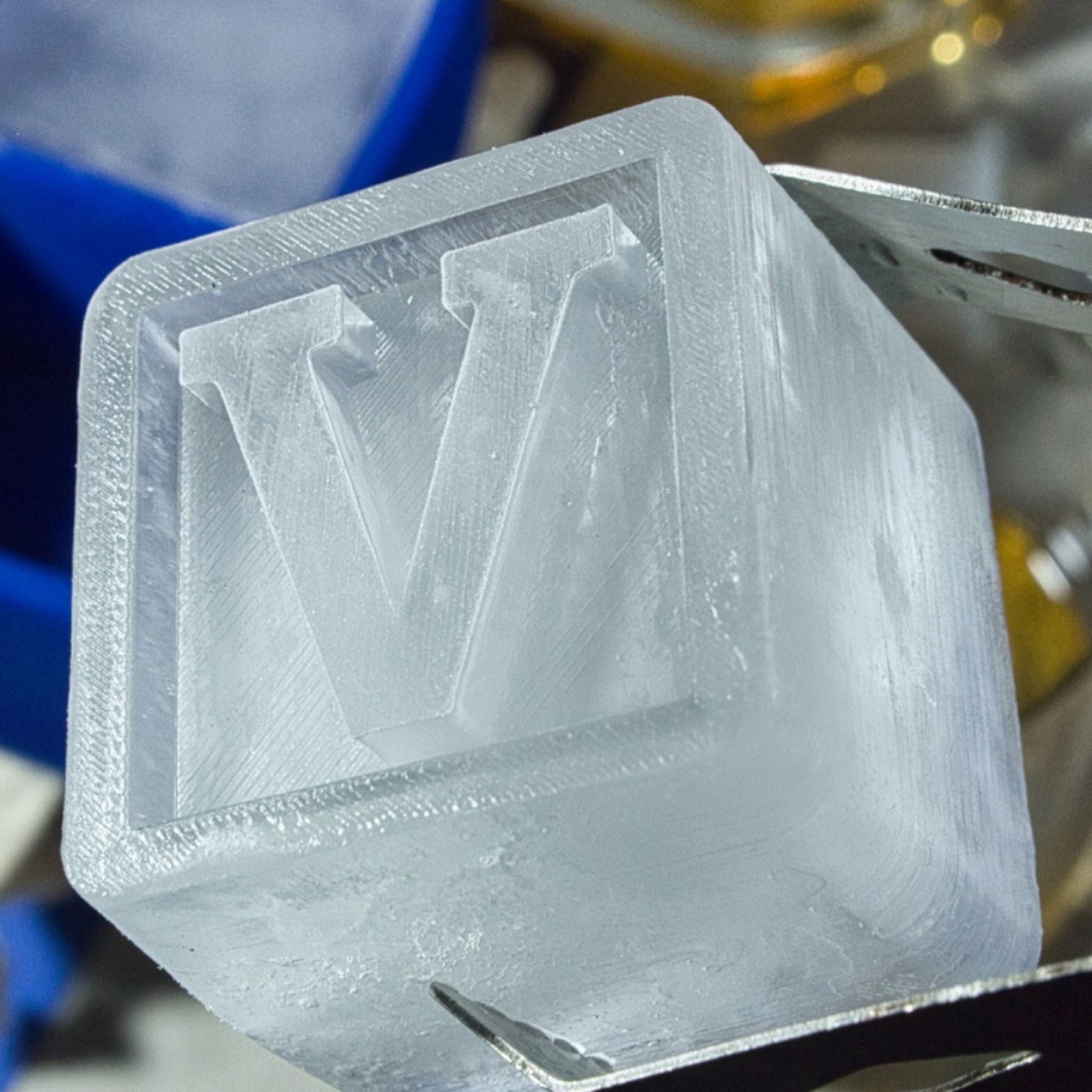 Detailed close-up of a V letter ice cube held by tongs, showcasing premium custom design for gifting and celebrations.