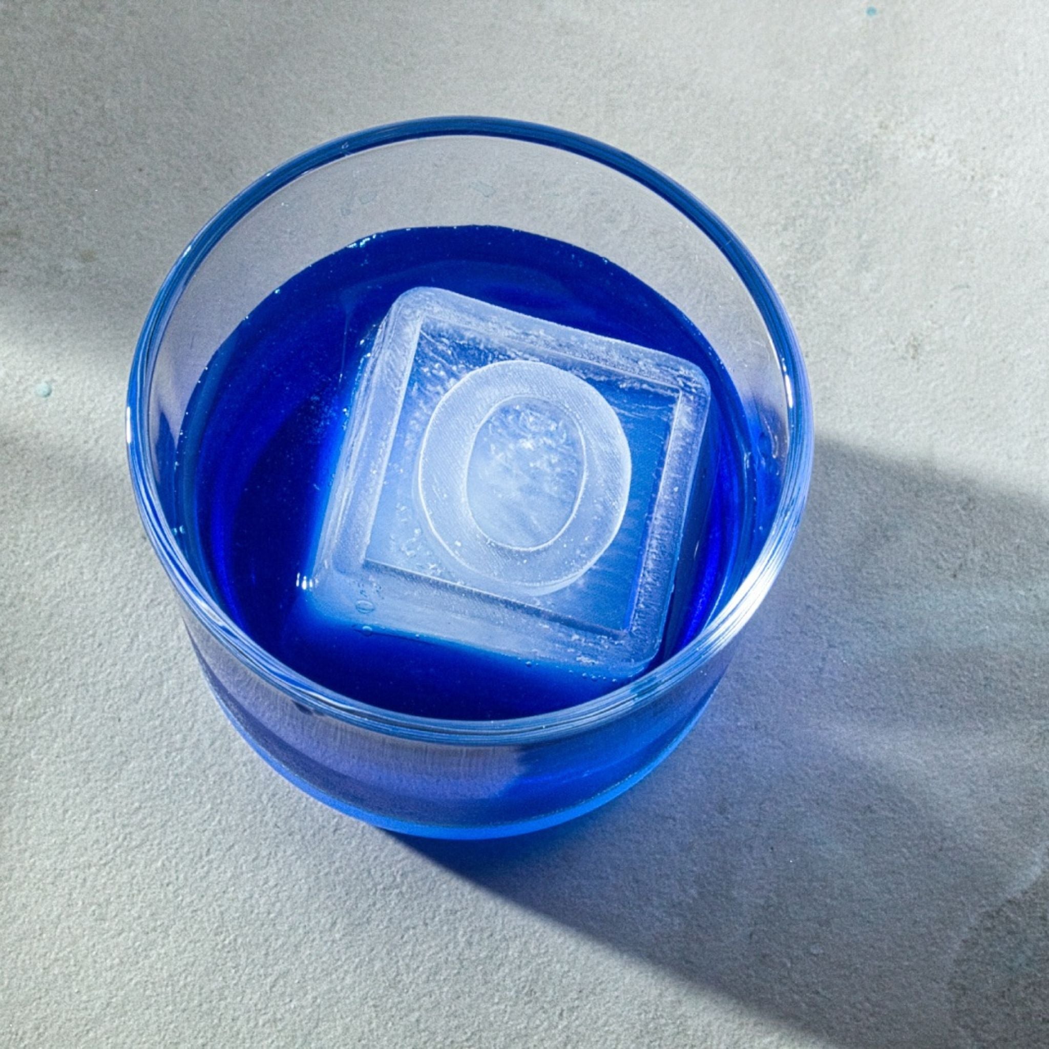 Blue cocktail with large clear O ice cube, showcasing premium drink presentation