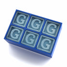 Blue silicone ice cube tray with six raised letter G designs in each cube slot
