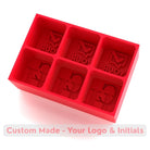 Bright red silicone ice tray with logo and initials cavities – handmade platinum silicone mould for promotional branding.