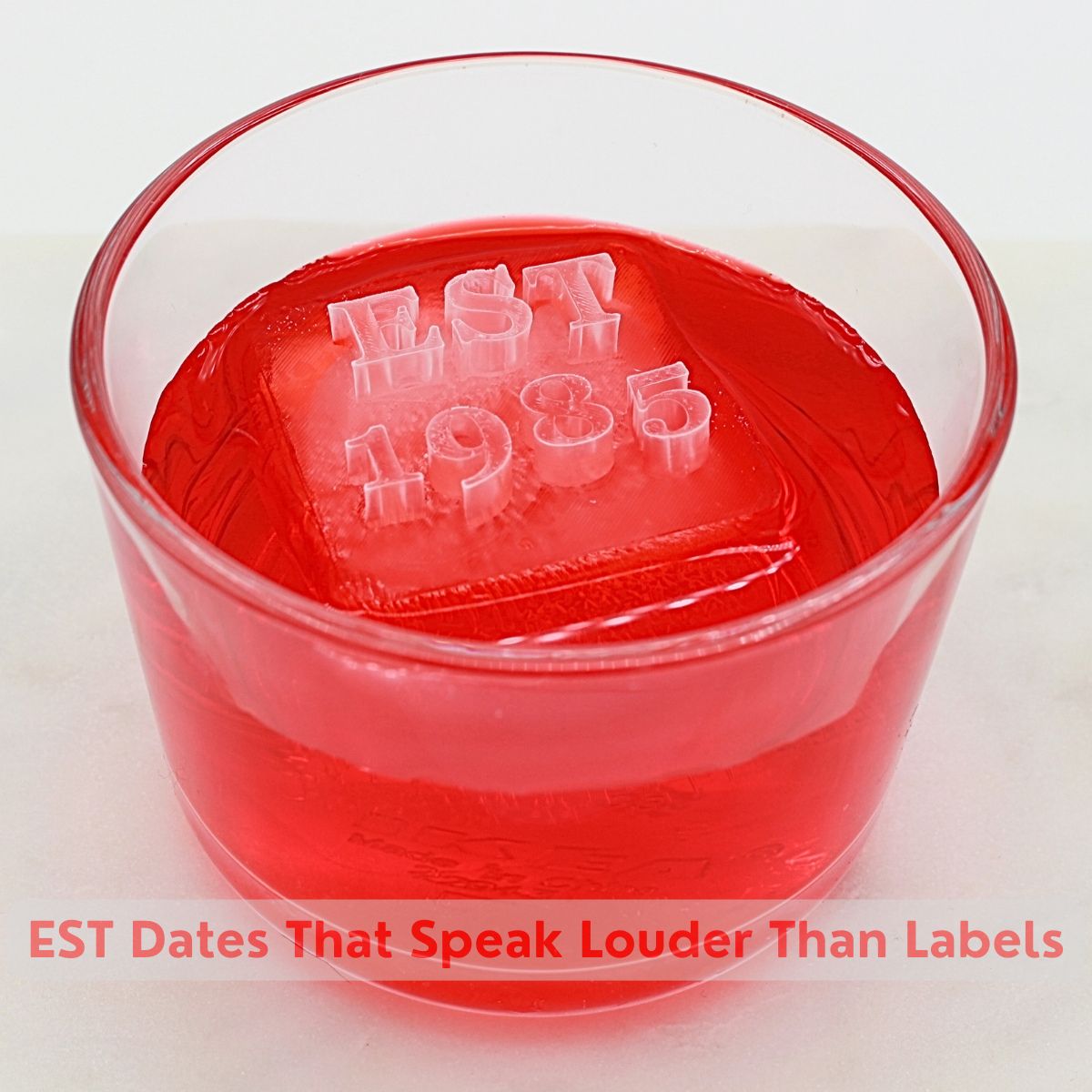 Red cocktail with custom EST 1985 ice cube featuring personalized establishment date - anniversary celebration drink