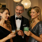 A well-dressed group celebrates Christmas with drinks featuring custom alphabet ice cubes. Guests in formal attire raise their glasses in a glamorous indoor setting.