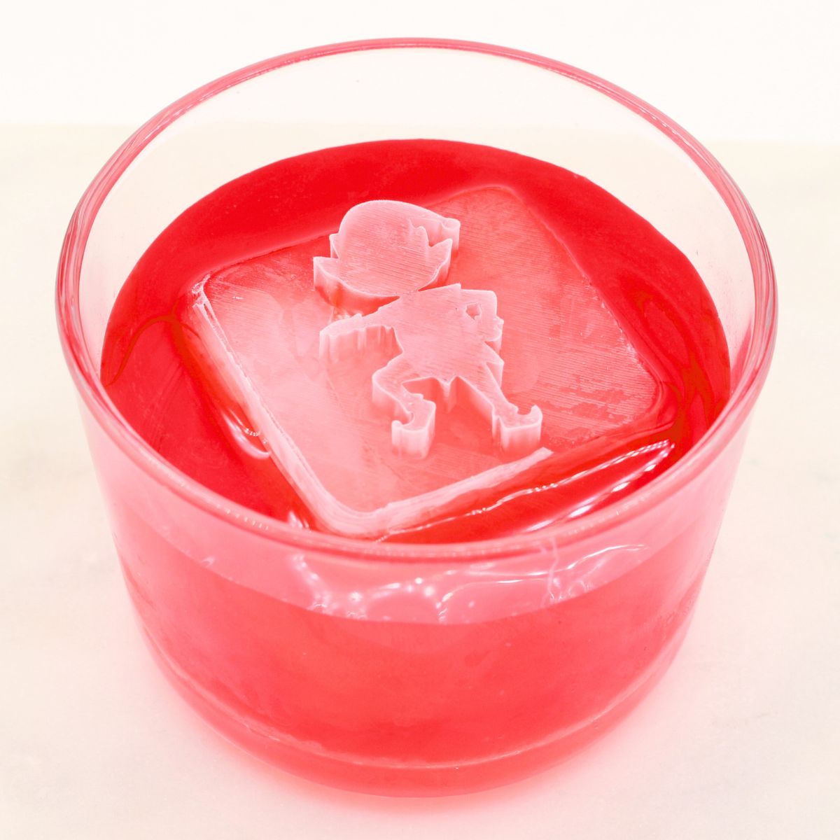 Bright red festive drink with a large elf ice cube on top, ideal for Christmas parties and entertaining.