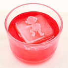 Bright red festive drink with a large elf ice cube on top, ideal for Christmas parties and entertaining.