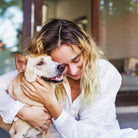 Woman in white shirt embracing her tan dog outside with eyes closed, expressing love and connection—ideal for personalised gifts for pet mums.
