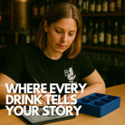 A woman in her 30s wearing a black Frothy Fox bar top sits at a table sketching a fox-themed logo while a blue 6-cube platinum-silicone ice tray rests beside her, realistic lifestyle setting.