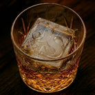 Close-up of a large custom J&S monogram ice cube in a rocks glass of whiskey