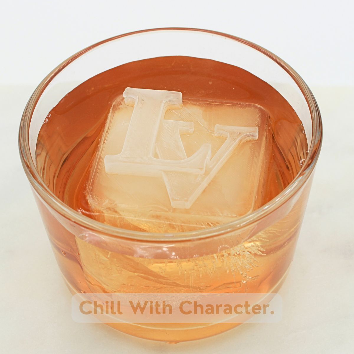 Close-up of a whisky glass with a custom LV monogram ice cube – stylish personalised barware gift for men.