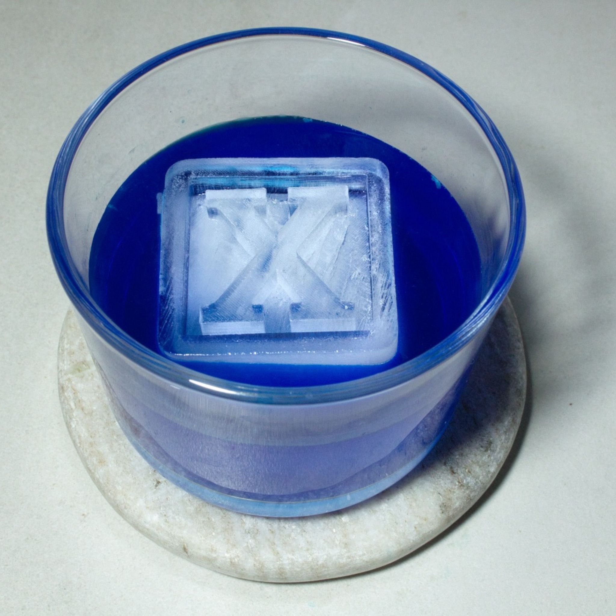 Custom letter X ice cube chilling a vibrant blue drink. Perfect for themed parties, gifting, or home bar inspiration.