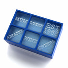 Blue 6-cube personalised ice tray showing words MUM, QUEEN, EST 1985, AMAZED, WINE, and CHEERS frozen in ice — a heartfelt handmade gift for Mum.