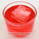 Bright red cocktail showcasing a customised ice cube with two initials linked by an ampersand, symbolising shared love.