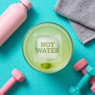 NOT WATER etched ice cube in a vodka soda next to a gym bottle