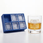 Blue Letter B ice tray next to a whiskey glass featuring a large B-embossed ice cube, bright natural light