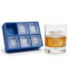 Blue silicone Letter J ice cube tray beside a rocks glass of amber whiskey chilled with a large clear ice cube stamped with the letter J, on a white background.