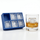 A blue silicone Letter W ice tray beside a whiskey glass containing amber liquor and a clear ice cube stamped with the letter W.