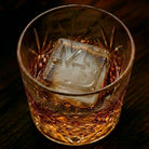 Monogrammed ice cube with custom initials and established year in a glass of whiskey
